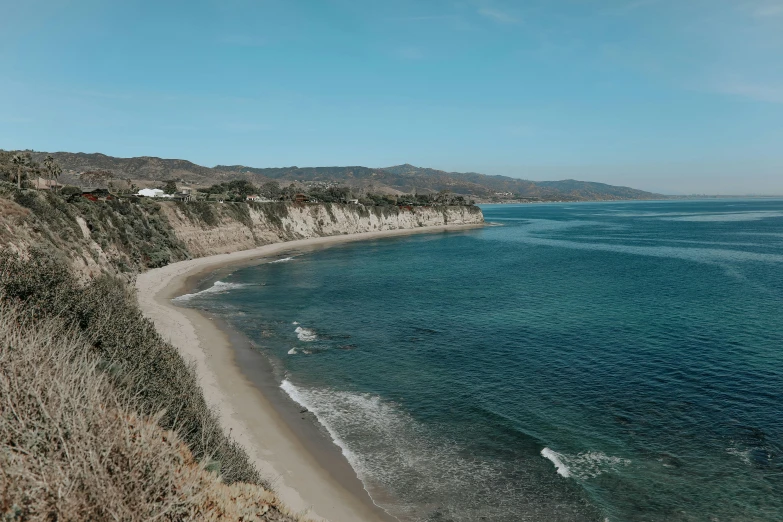 an empty beach near some water and mountains