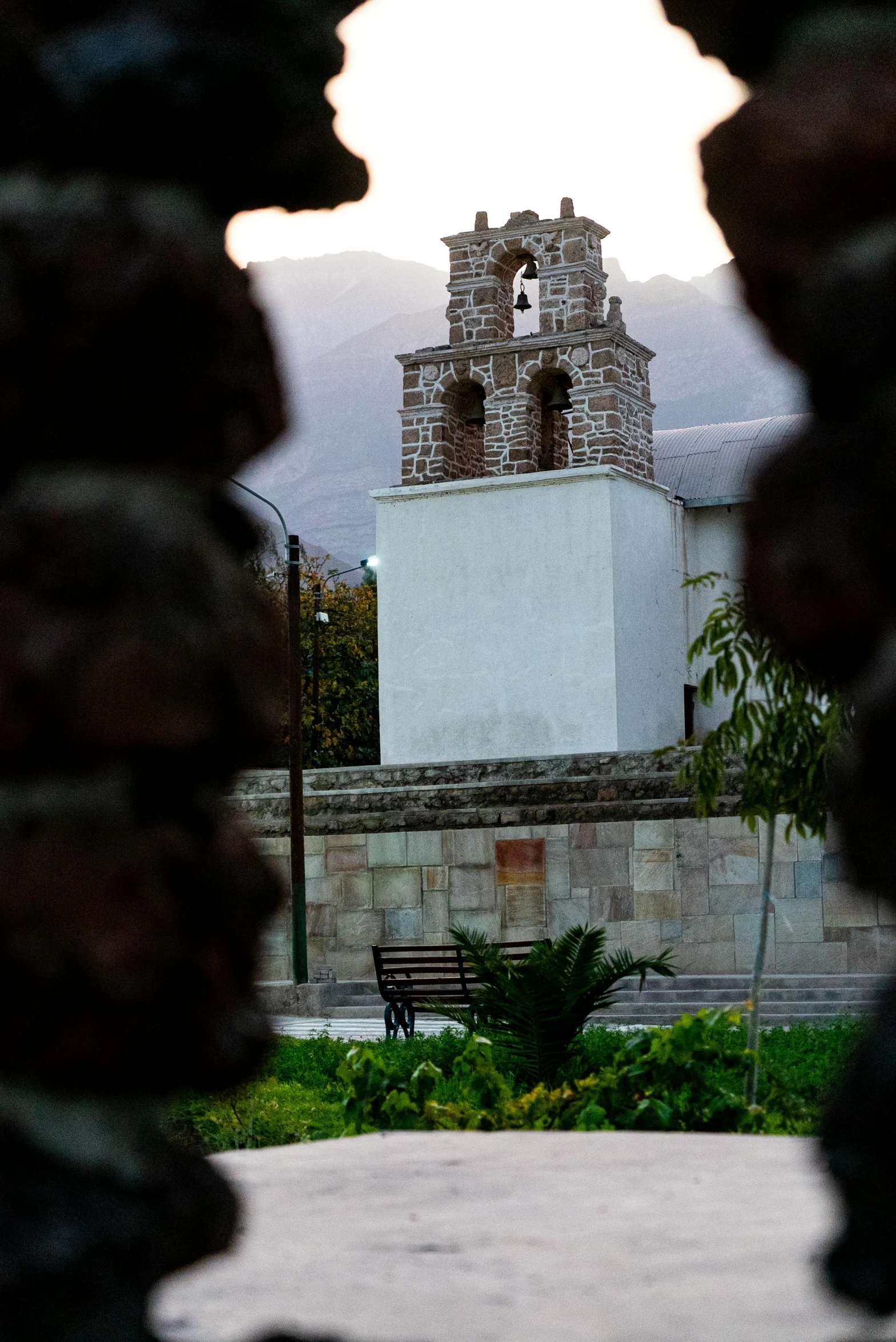 view through gate, showing a small white building with a clock tower in the background