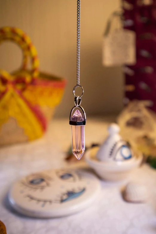 a necklace with a hanging glass bead hangs from a necklace chain