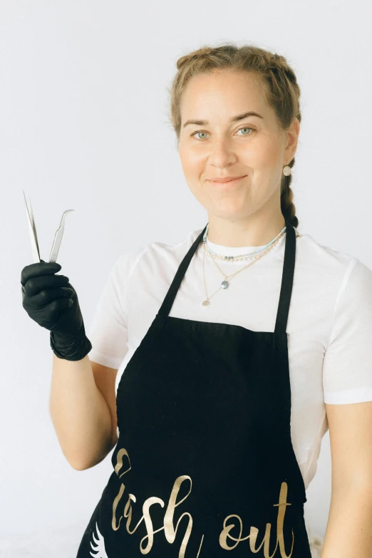 a smiling woman in an apron holding a pair of scissors