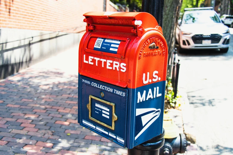 a blue and orange mailbox next to a sidewalk