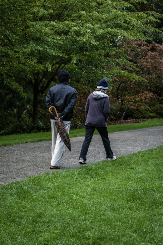 a couple walking down the trail holding umbrellas