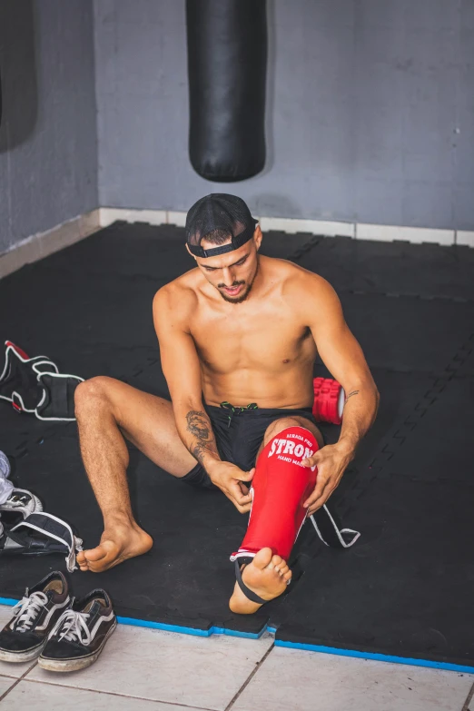 shirtless man in boxing gloves tying his shoe