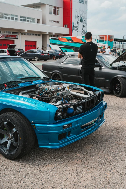 some people and two cars with one car showing its engine