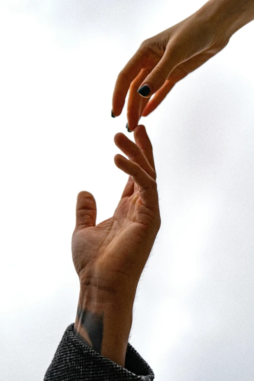 two people reaching out toward a frisbee that is flying in the sky