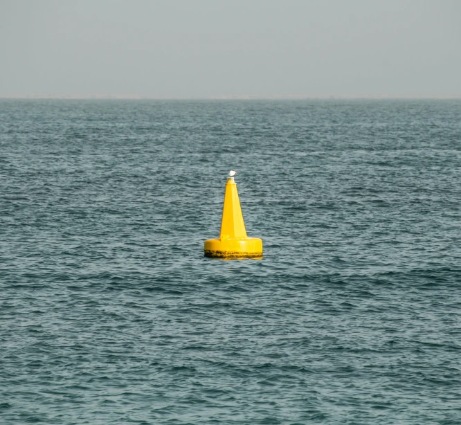 a yellow pole sitting in the middle of a large body of water