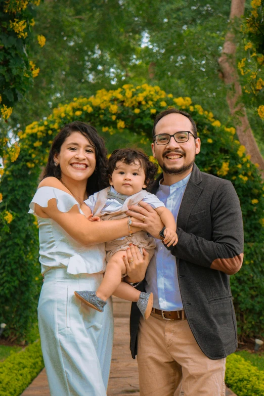 two men and a woman pose for the camera with a baby boy