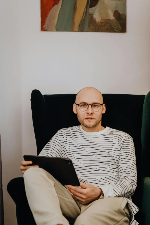 a man in a chair holding an album while sitting down