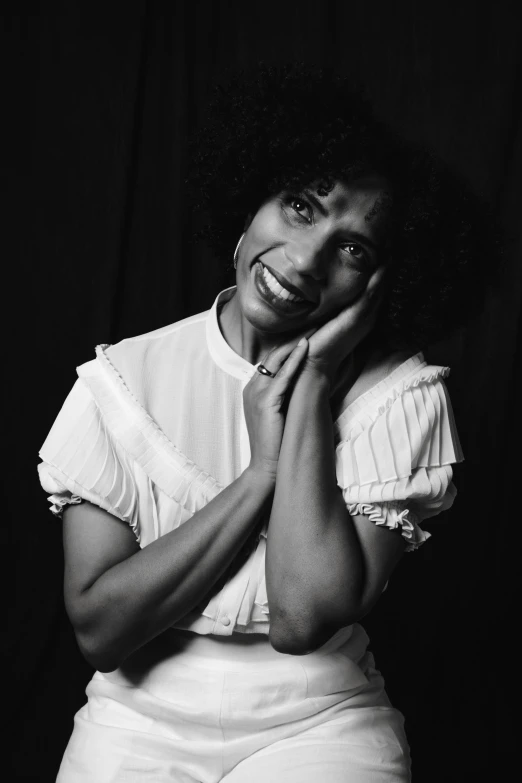 a woman with a afro smiles and poses in white dress