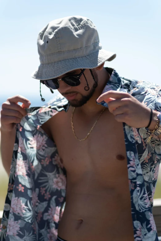 shirtless man putting on clothes by the ocean