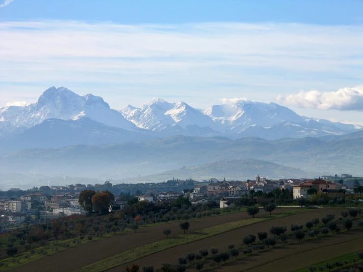 the large mountains are in the distance from some village