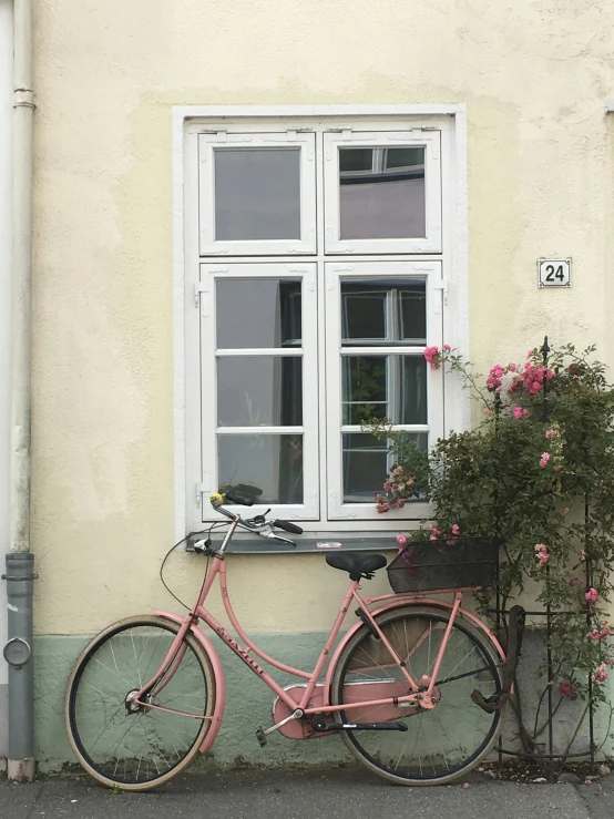 a pink bicycle parked next to a window