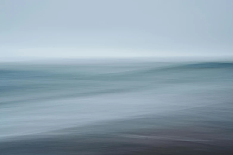 a blurry image of water and sand, with dark waves