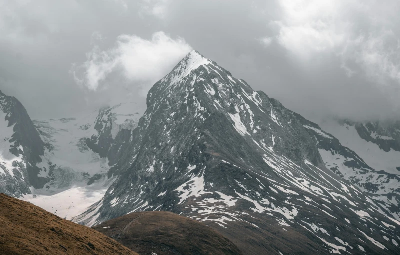 a tall mountain with a brown grassy field underneath