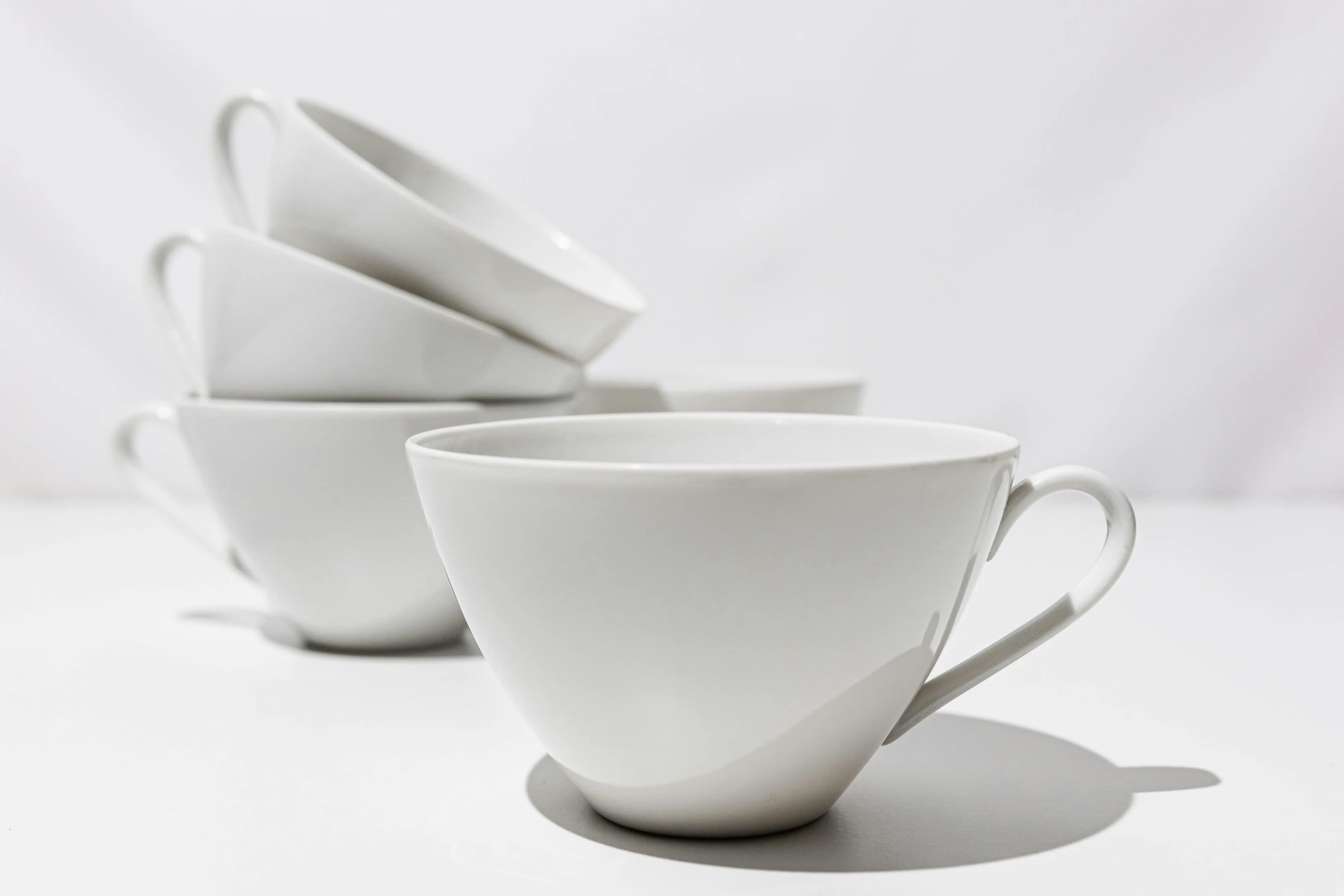 a white set of five cups, with one saucer and six spoons