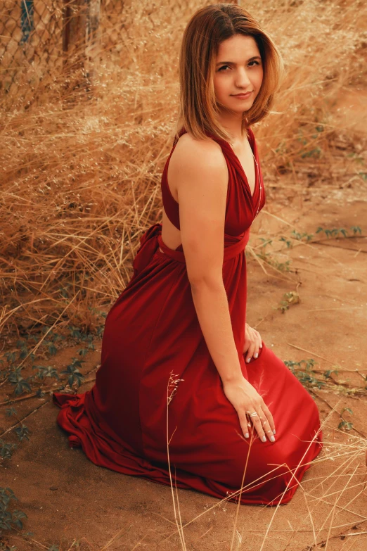 a woman in red is sitting on the dirt