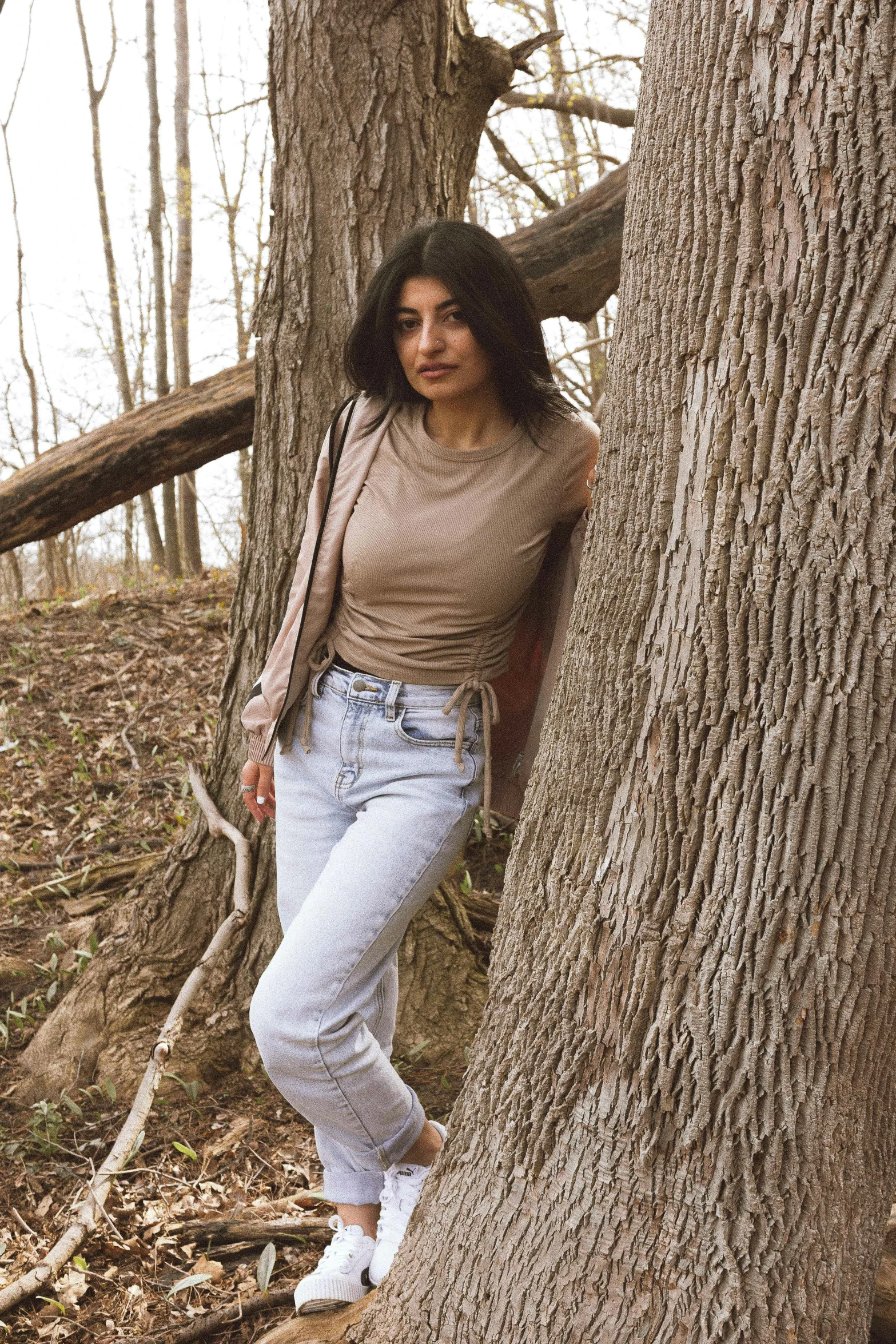 a woman leaning on a large tree in the woods