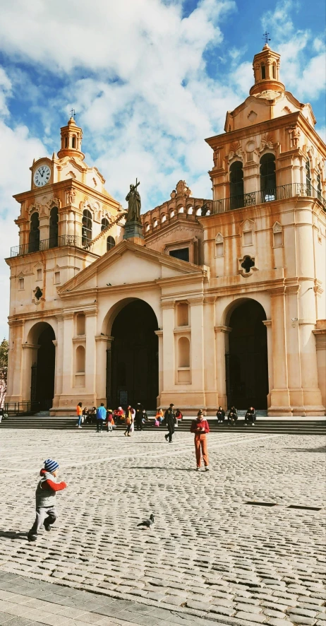 people are in front of a church while children play in the courtyard