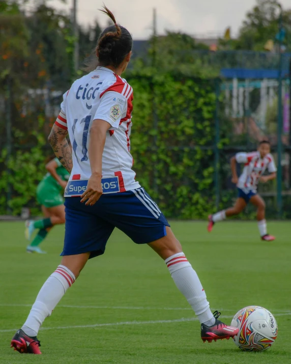 two soccer players on the field and one getting ready to kick the ball