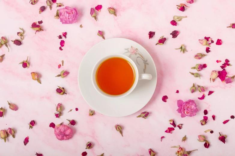 rose petals scattered around a white cup of tea