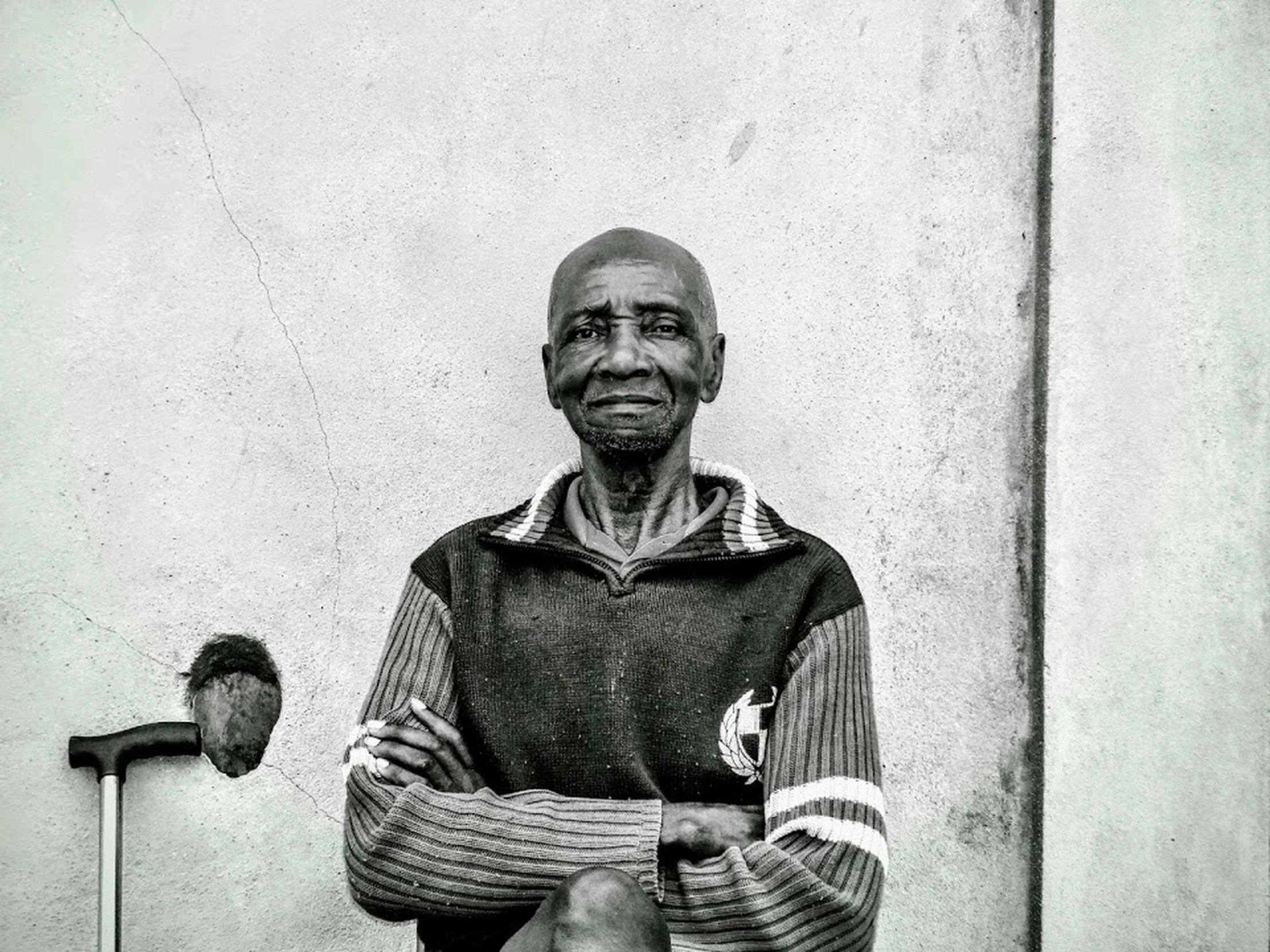 a man standing next to a white building with his hands folded