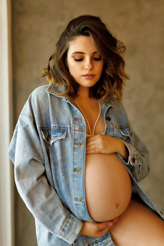 pregnant woman's jeans jacket standing next to her belly
