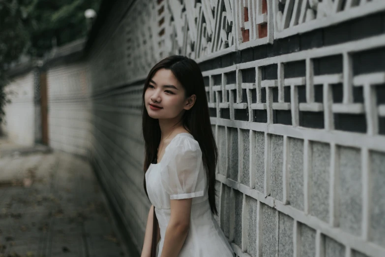 a young asian woman leaning on a wall