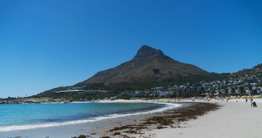 the beach is near a mountain and blue sky