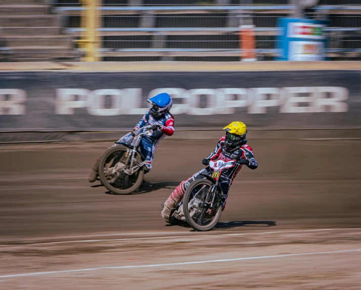 two men in helmets racing on dirt bikes