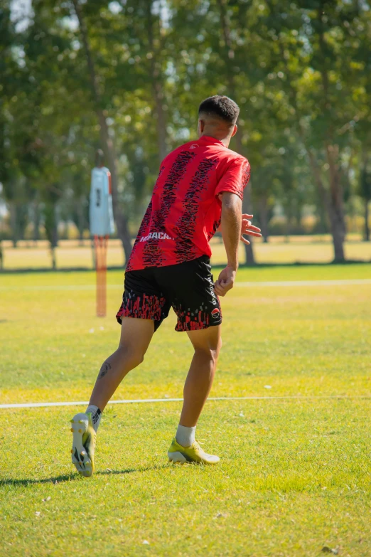 man on grass about to kick ball with a frisbee