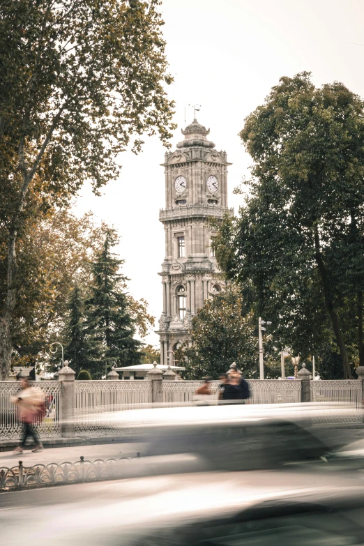 a group of people walk past a tall clock tower