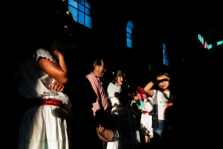 children wearing costumes stand next to a man in a dark room