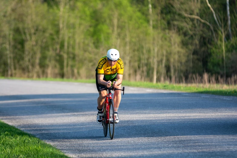 a man in a yellow and green shirt riding a red bicycle