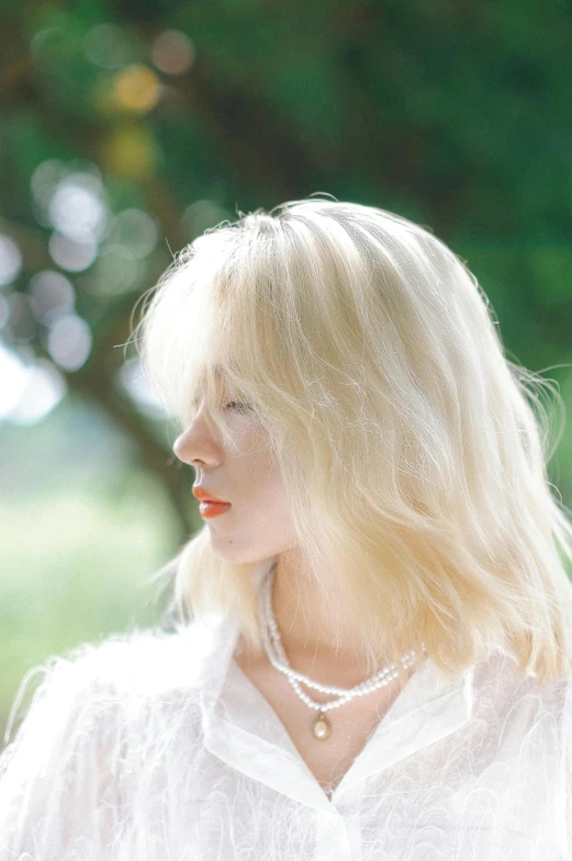 a beautiful blonde woman wearing a white blouse and pearls