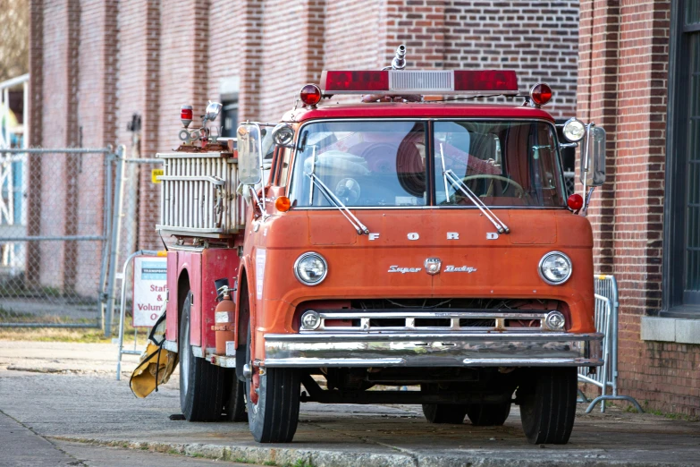 an old fire truck is parked in front of the brick building