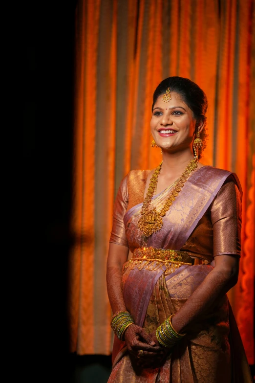 woman with gold jewelry smiling in dark po