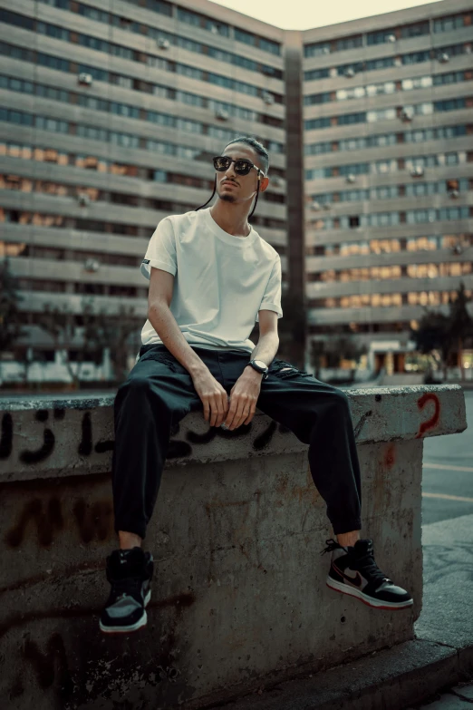 a man with black headphones sitting on concrete ledge