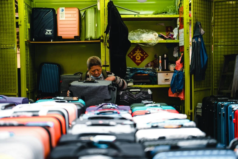 a man sits in front of many different pieces of luggage