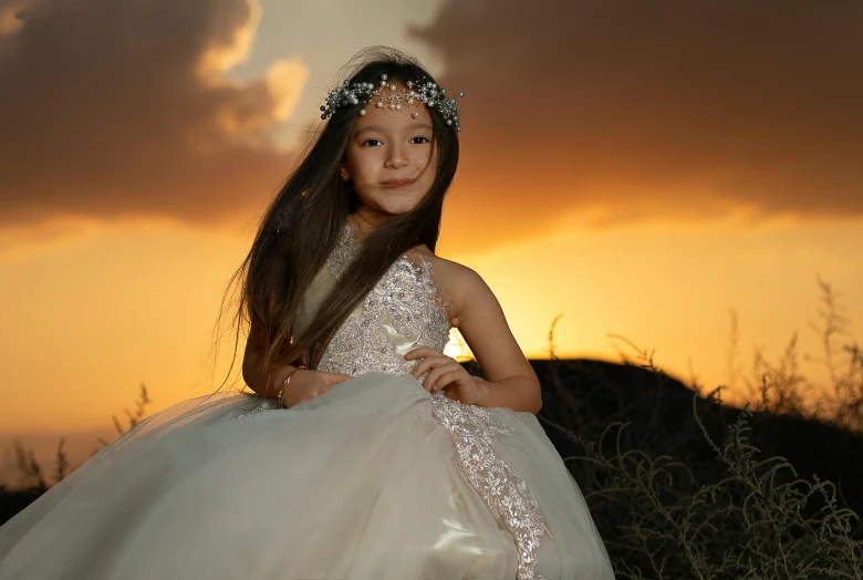 a little girl in a dress at sunset