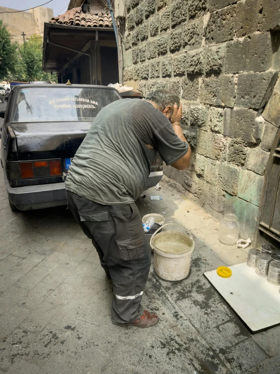 a man bending down to paint a brick wall