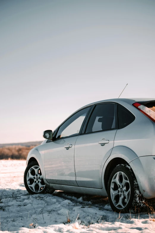 a silver car is parked in the snow