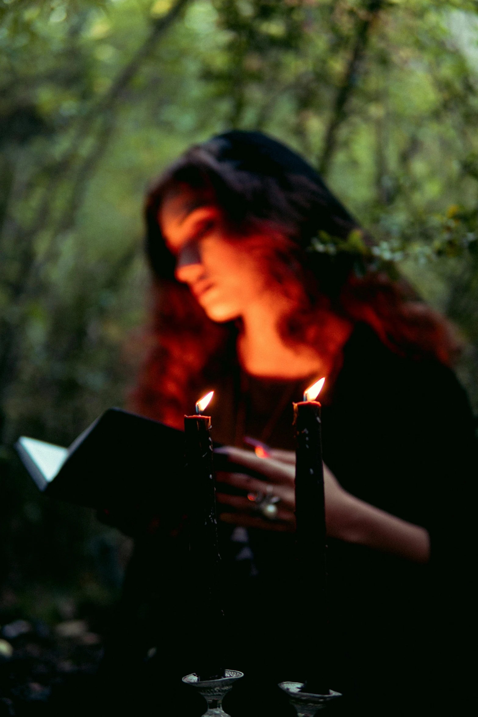 a young woman looking at some candles in a forest