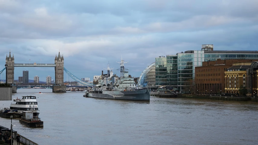 boats parked along a canal next to tall buildings and a bridge