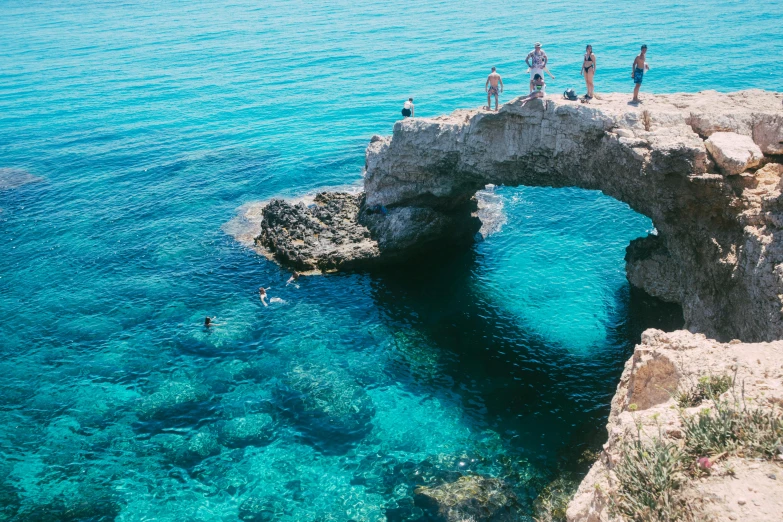 some people are standing on an arch in the water