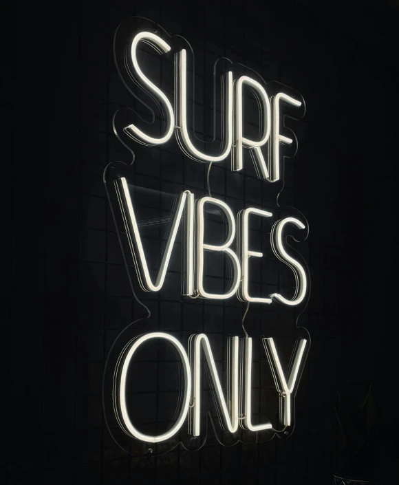 the words surf vibes only are lit up with neon