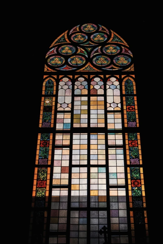 a large window in a dark building that has lots of stained glass