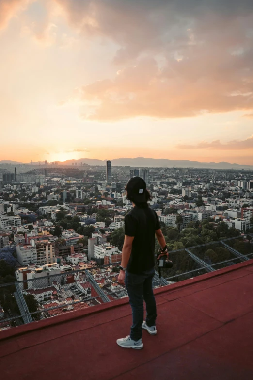 person standing at the edge of a high rise and looking down on a city