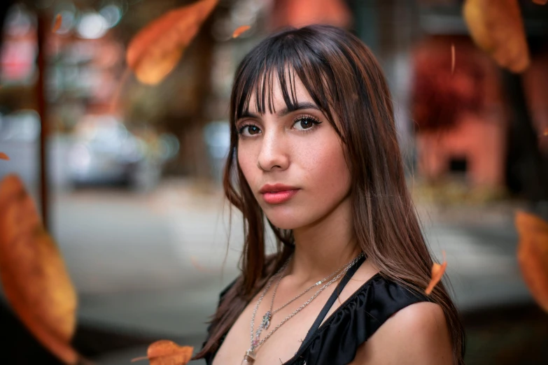 a woman looking directly at the camera and leaves in the background