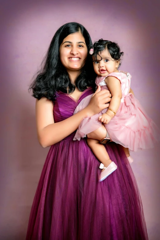 a lady is smiling and holding a baby girl in her arms