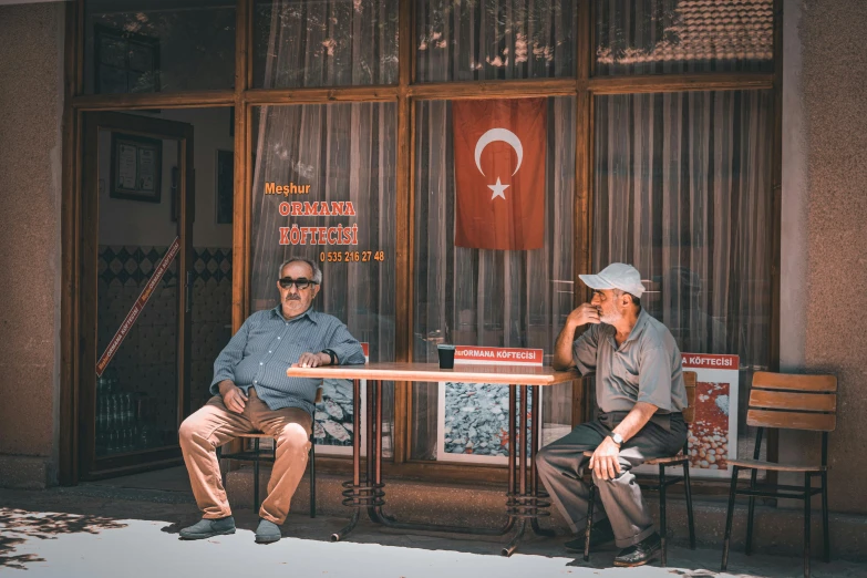 two men sitting at table talking outside of business